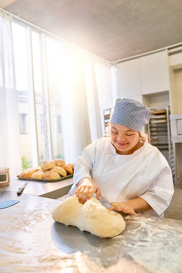 Smiling young woman with Down Syndrome kneading dough
