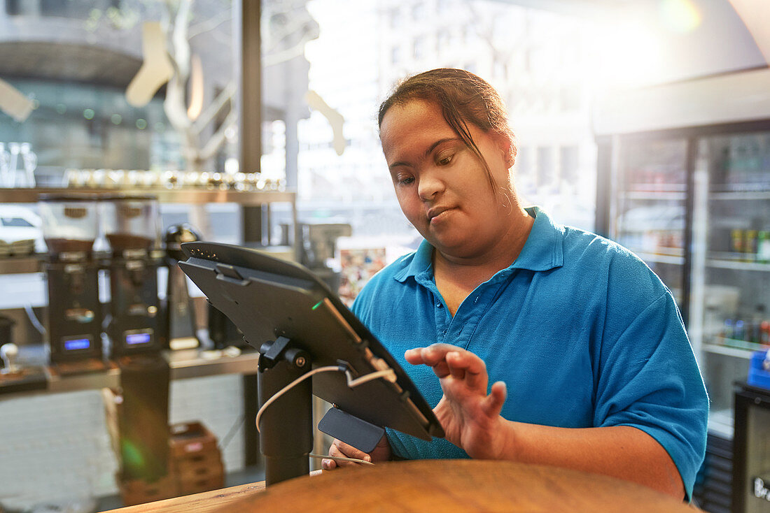 Woman with Down Syndrome working at cash register in cafe