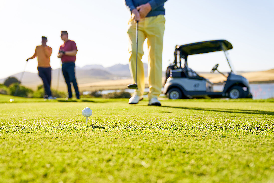 Male golfer preparing to tee off on sunny golf course