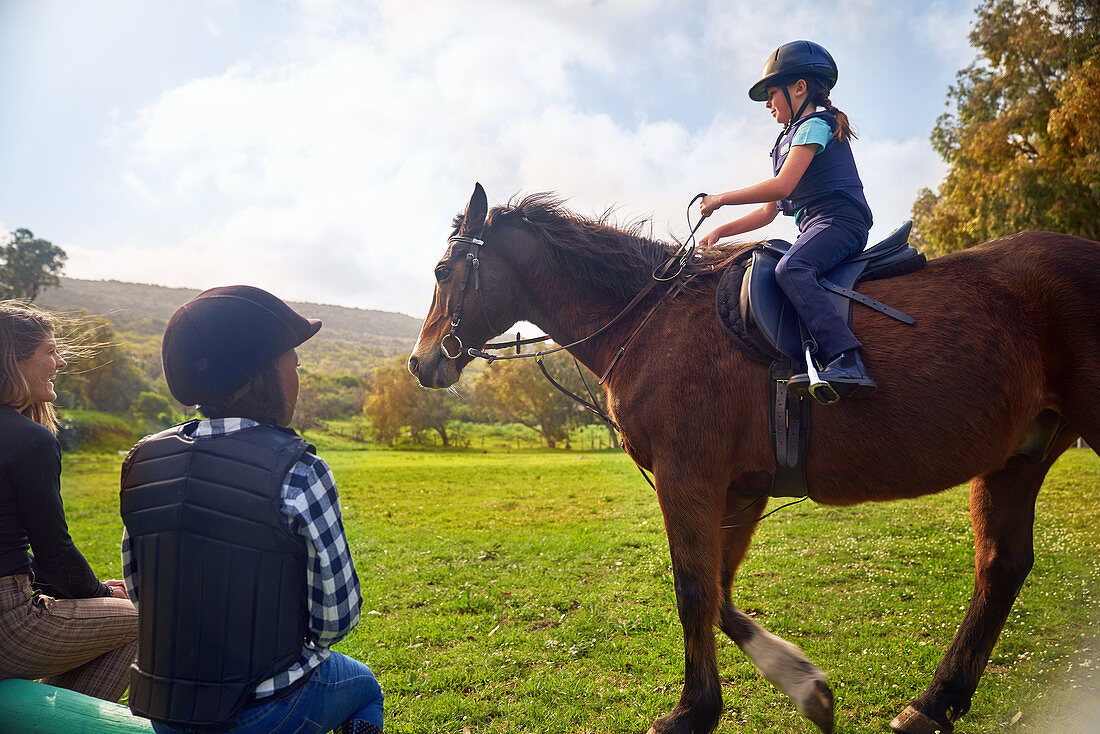 Girl learning horseback riding in rural grass paddock