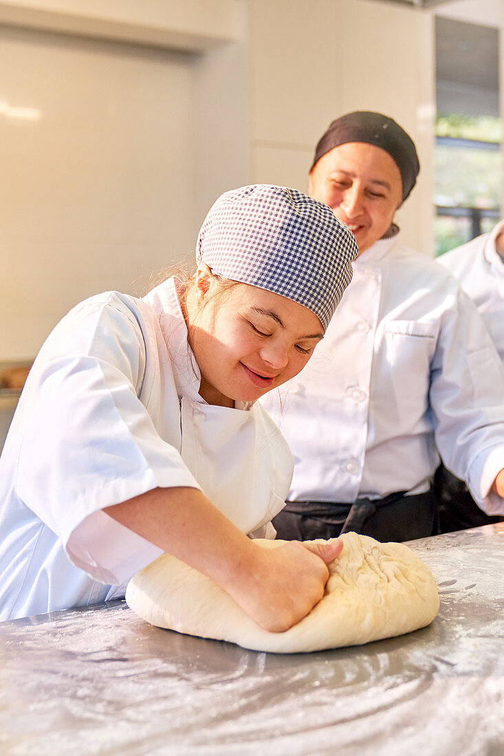 Woman with Down Syndrome kneading dough in baking class