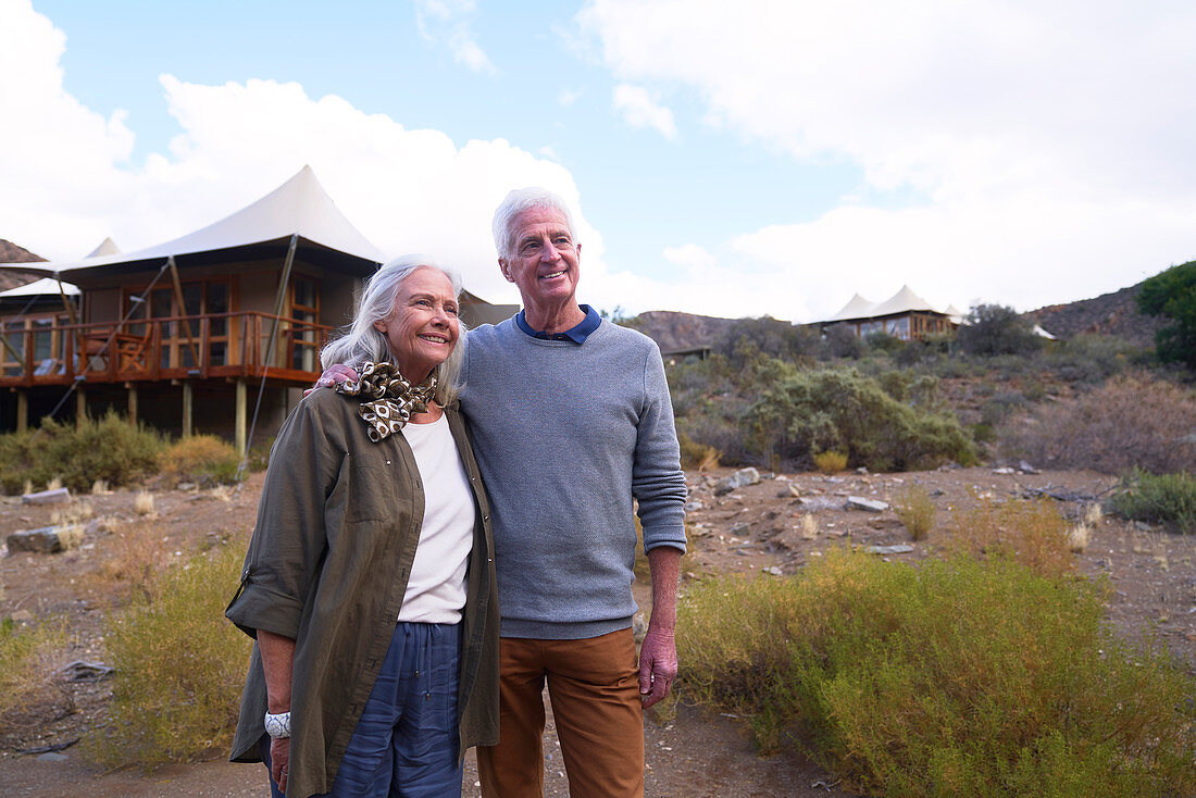 Happy senior couple outside safari lodge cabin
