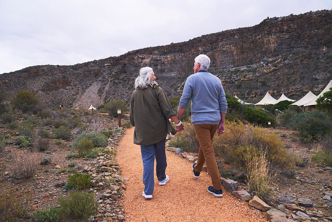 Senior couple holding hands on footpath