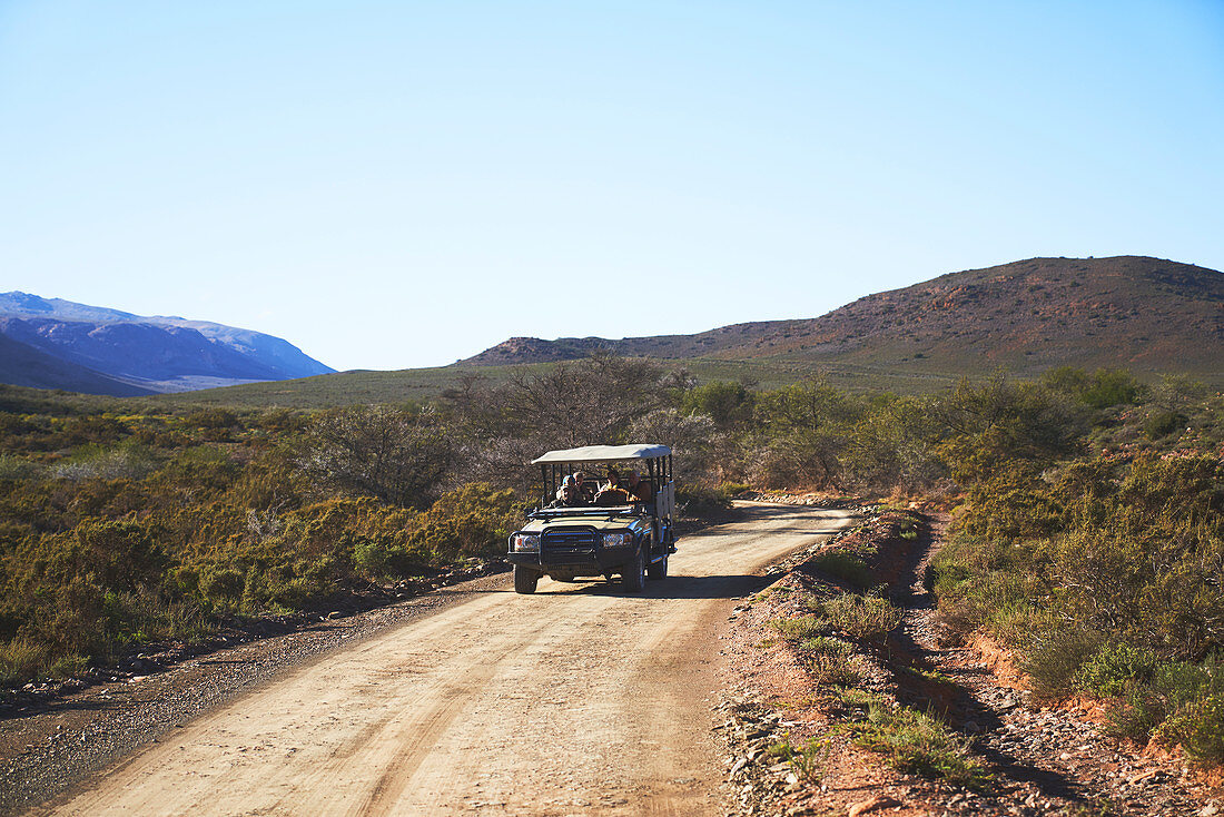 Safari vehicle on sunny emote dirt road South Africa