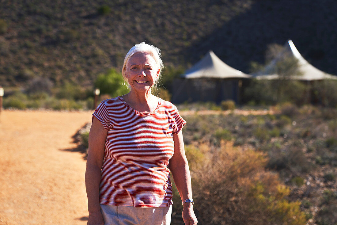 Senior woman on sunny footpath outside safari lodge