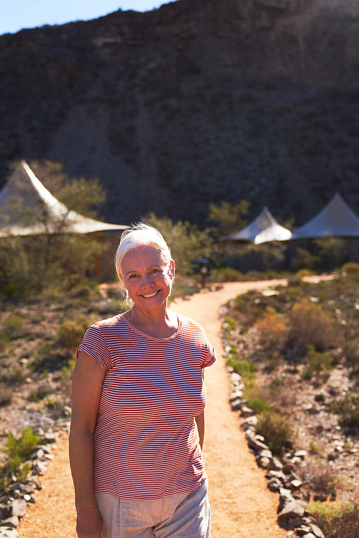 Senior woman on footpath outside safari lodge cabins