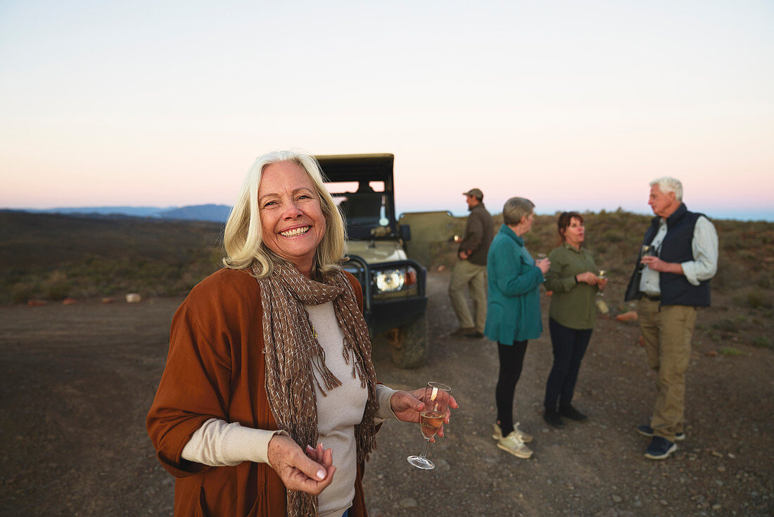 Portrait happy senior woman drinking champagne on safari