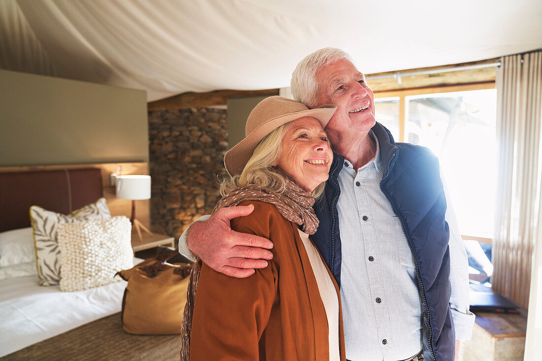 Carefree senior couple hugging in safari lodge hotel room