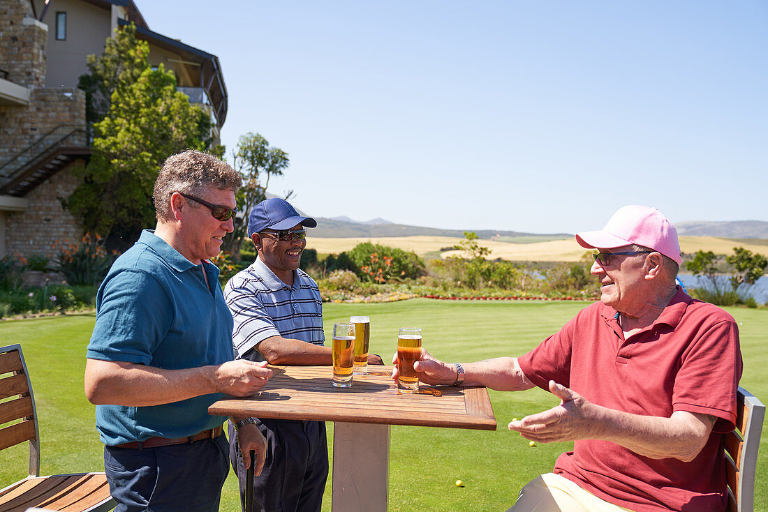 Happy mature golfers drinking beer at clubhouse
