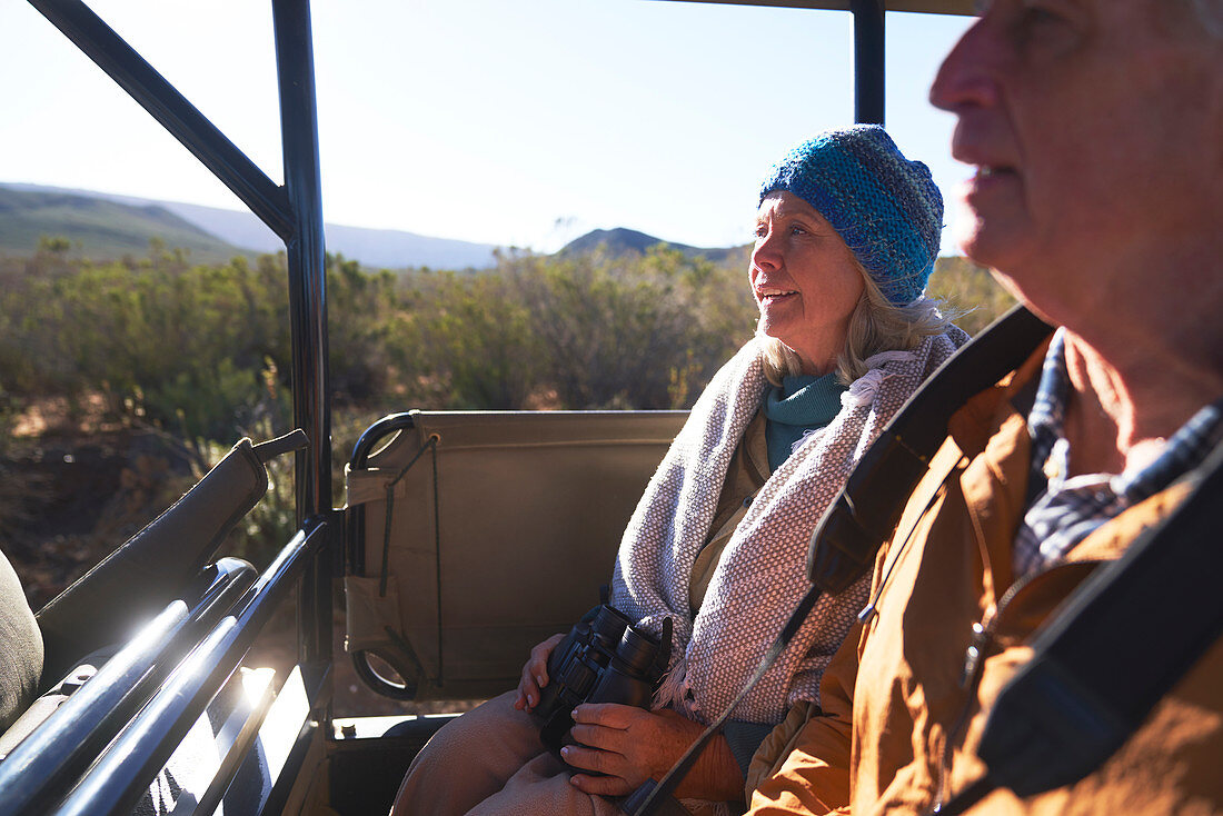 Happy senior couple riding in off-road safari vehicle
