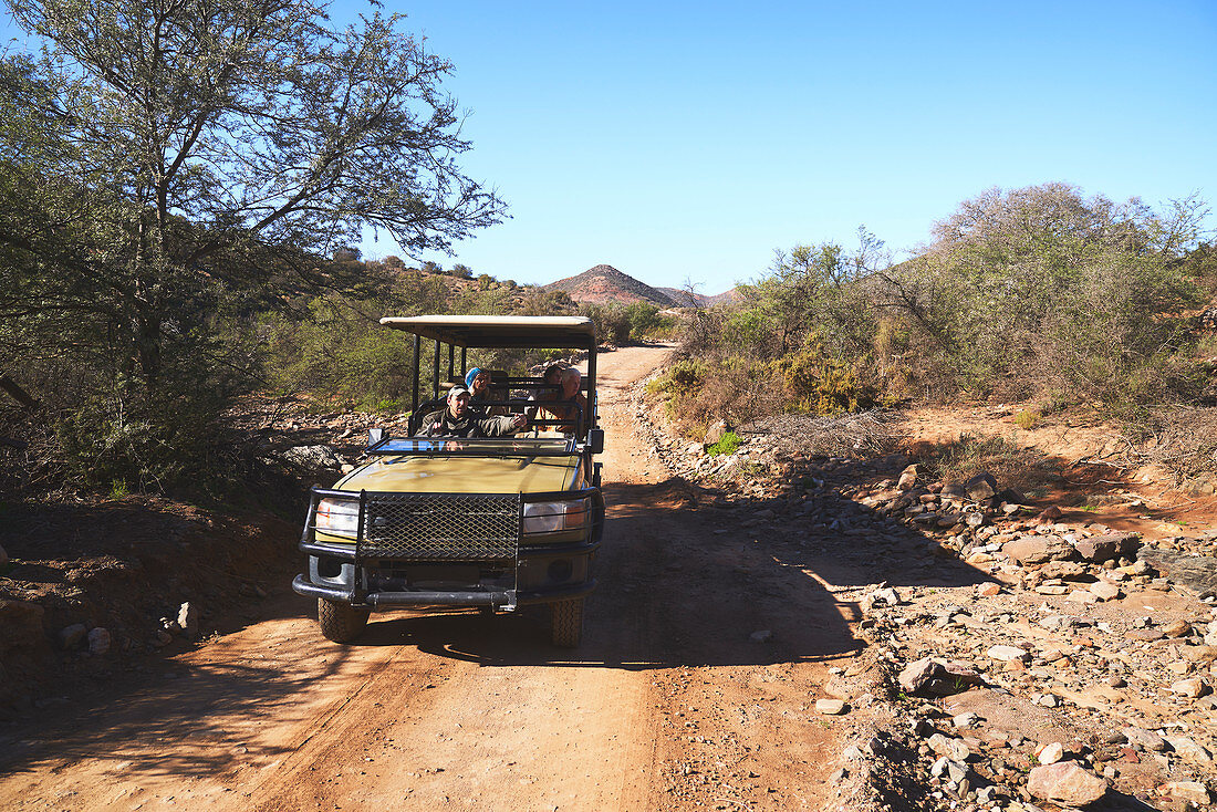 Group riding in off-road vehicle on sunny dirt road