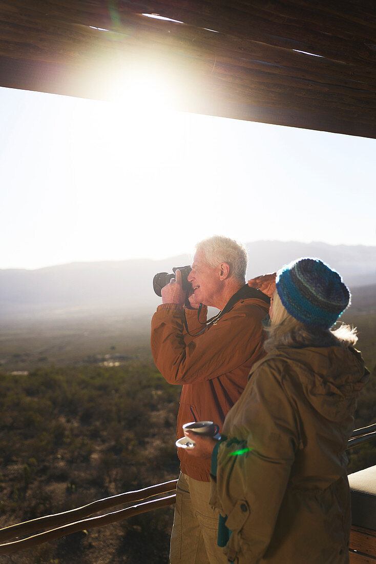 Senior couple with camera on sunny safari balcony