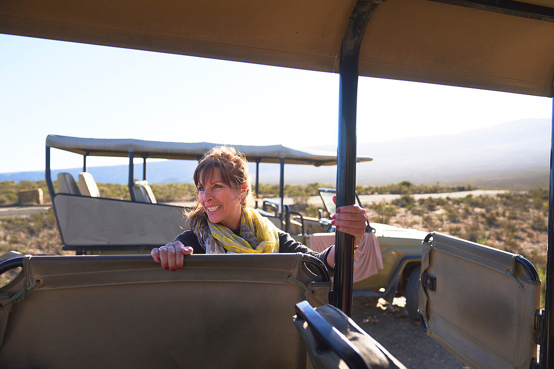 Happy mature woman getting into safari off-road vehicle