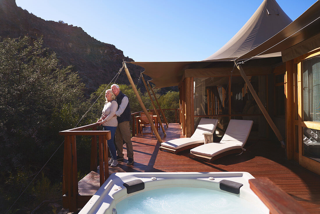 Affectionate couple on sunny luxury safari lodge balcony