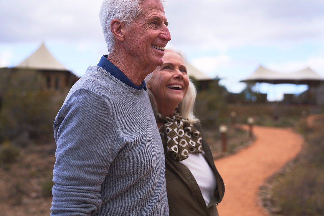 Happy senior couple on footpath outside safari lodge