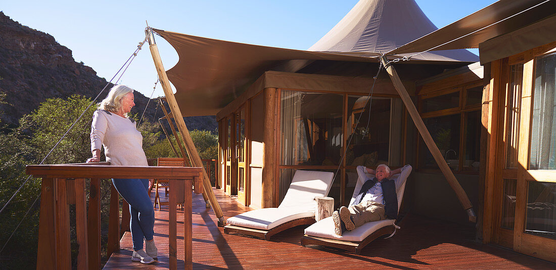 Couple relaxing on sunny luxury safari lodge balcony
