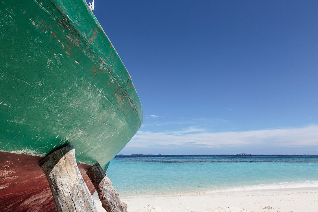 Boat propped up on ocean beach, Maldives