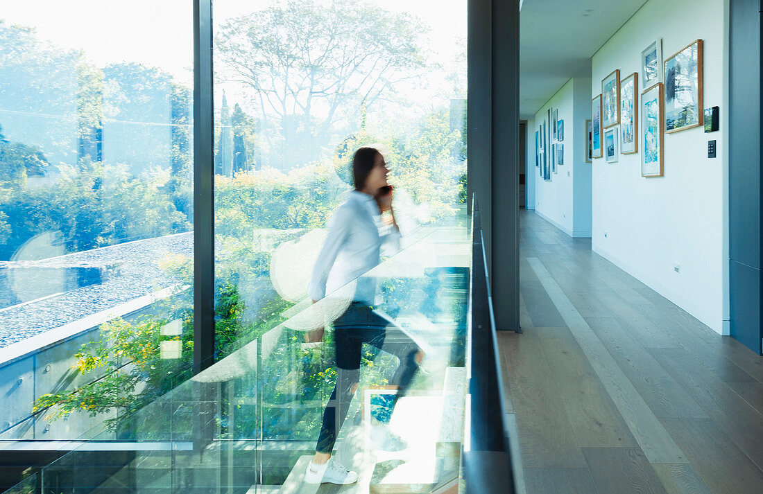 Woman ascending stairs in modern, luxury home