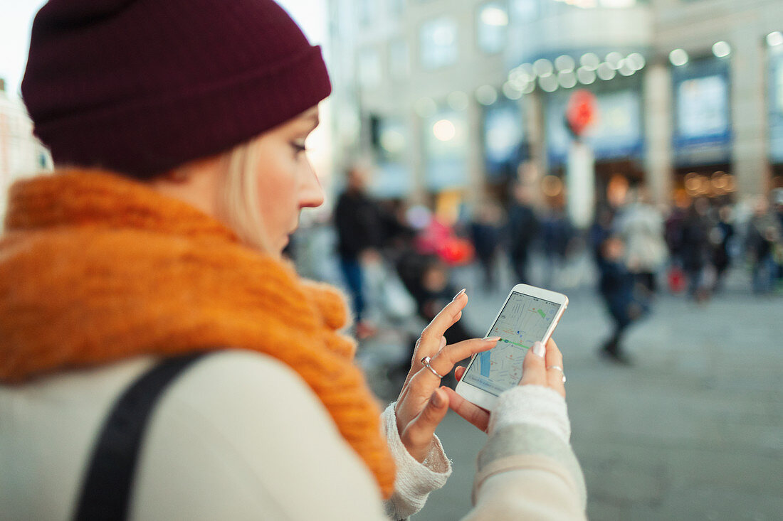 Woman using GPS on smart phone on urban street