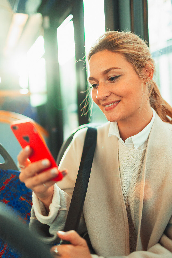 Woman using smart phone on bus