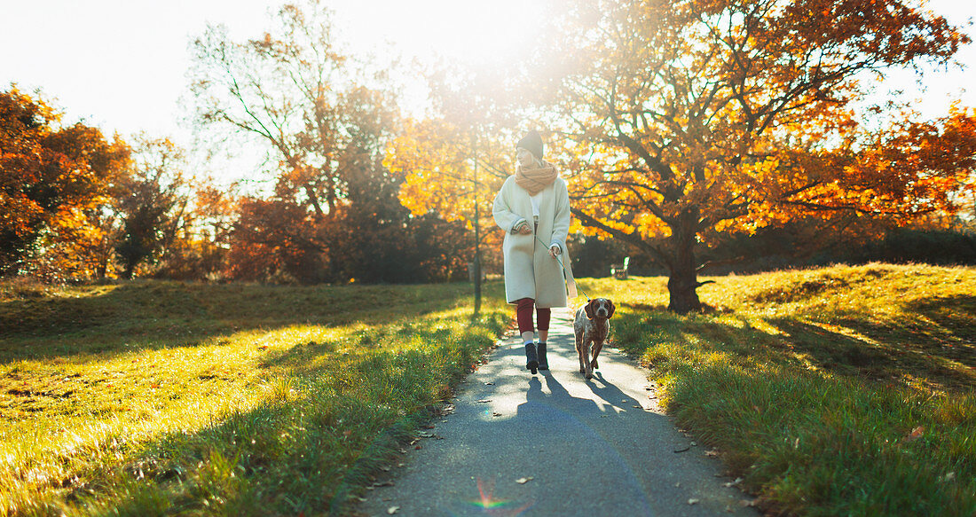 Woman walking dog in autumn park