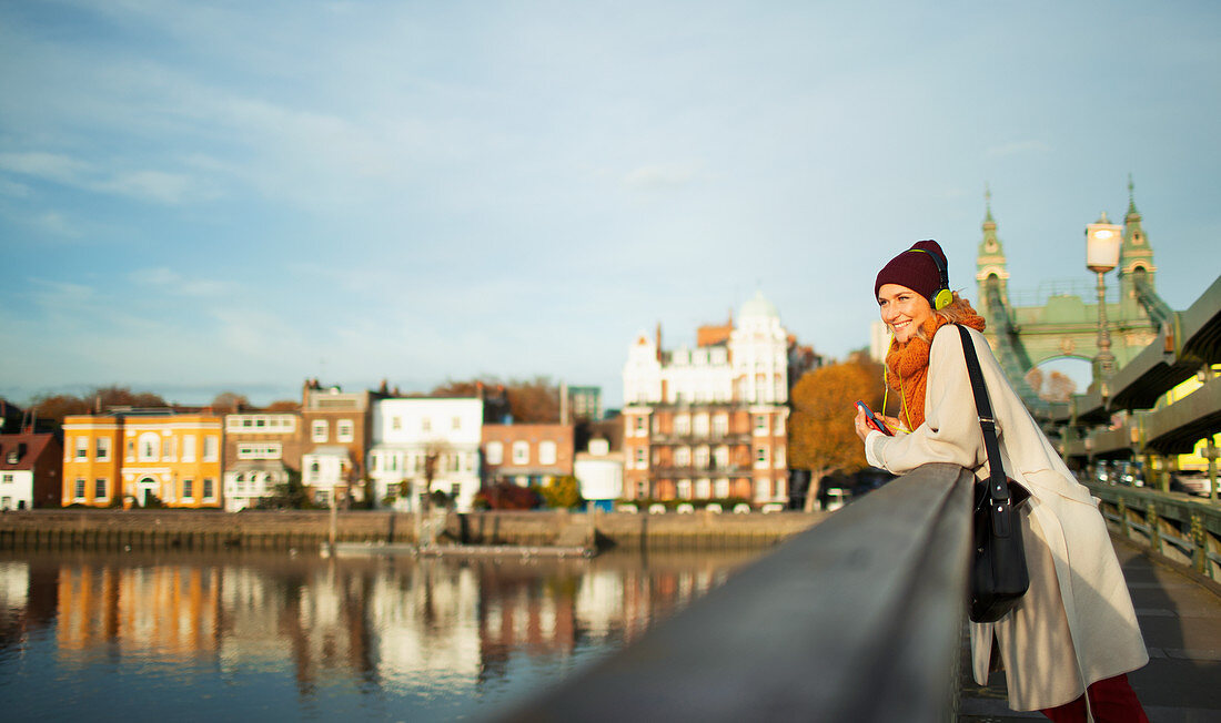 Woman in stocking cap and scarf on urban autumn bridge