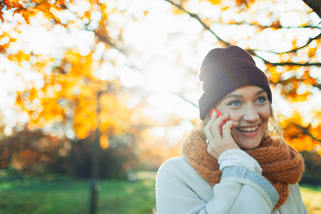 Woman talking on smart phone in autumn park