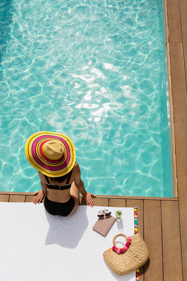Woman in sun hat and bikini relaxing at poolside