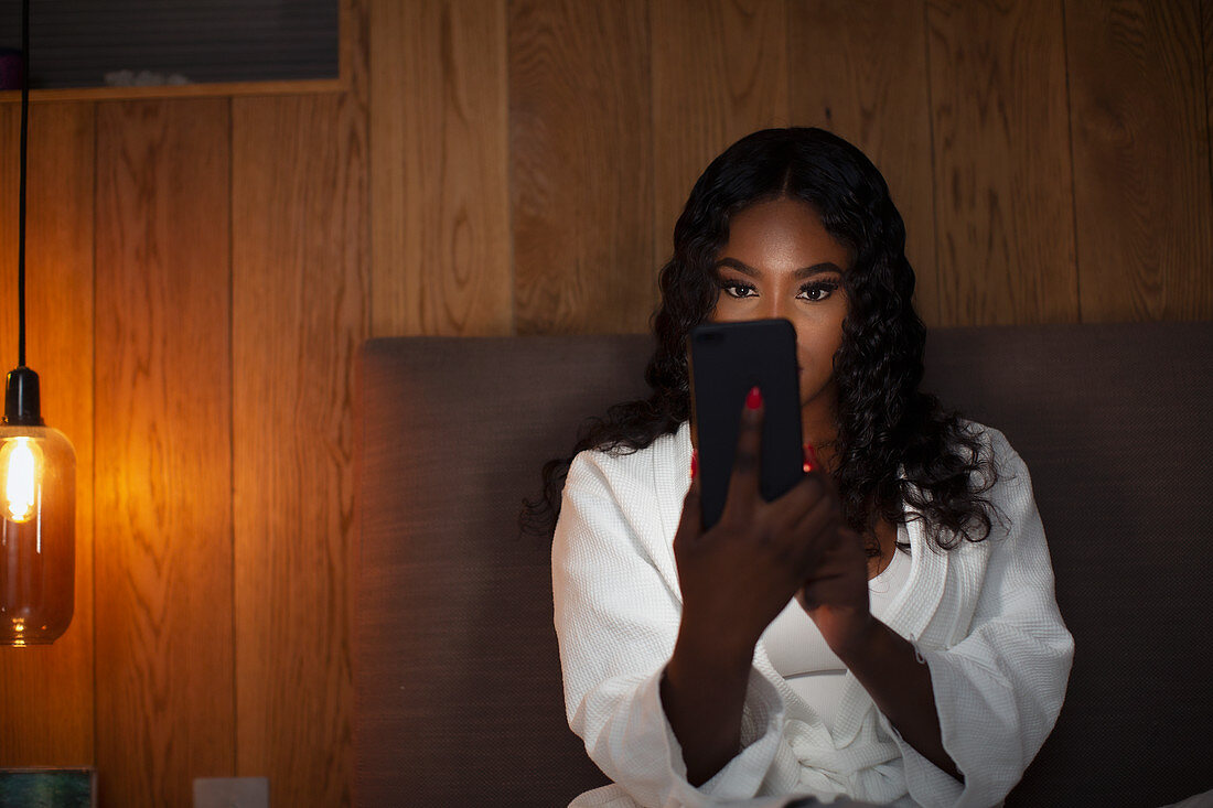 Woman using smart phone in dark bedroom