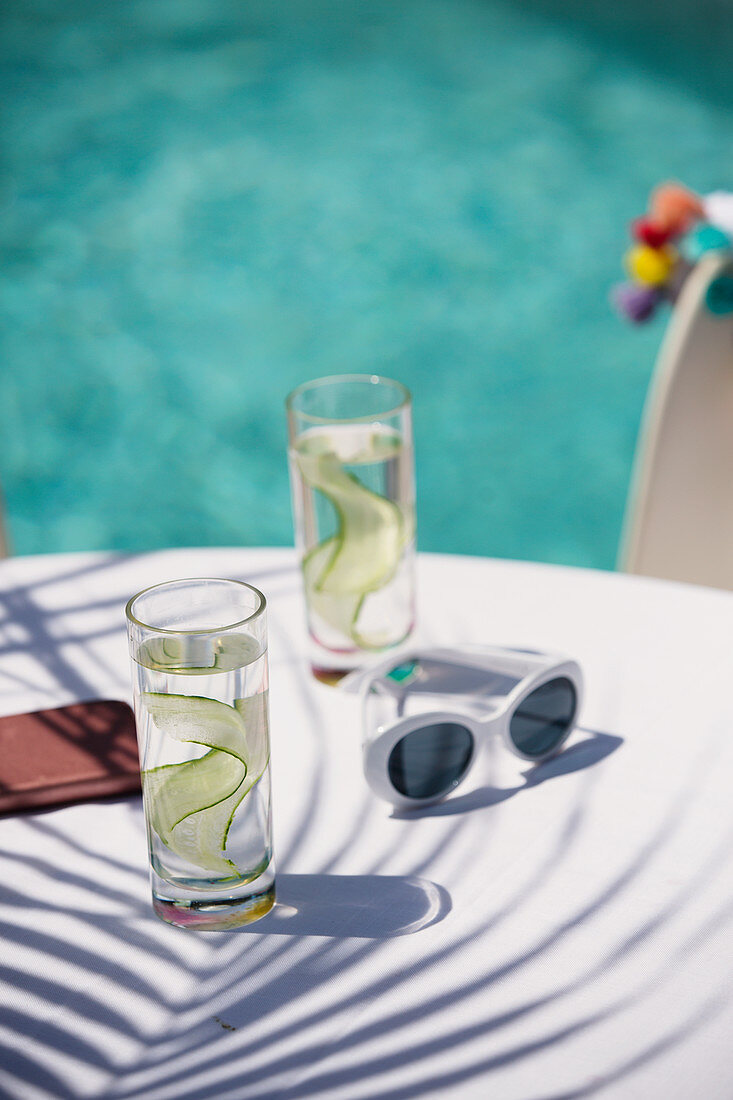 Cucumber water and sunglasses on poolside patio table