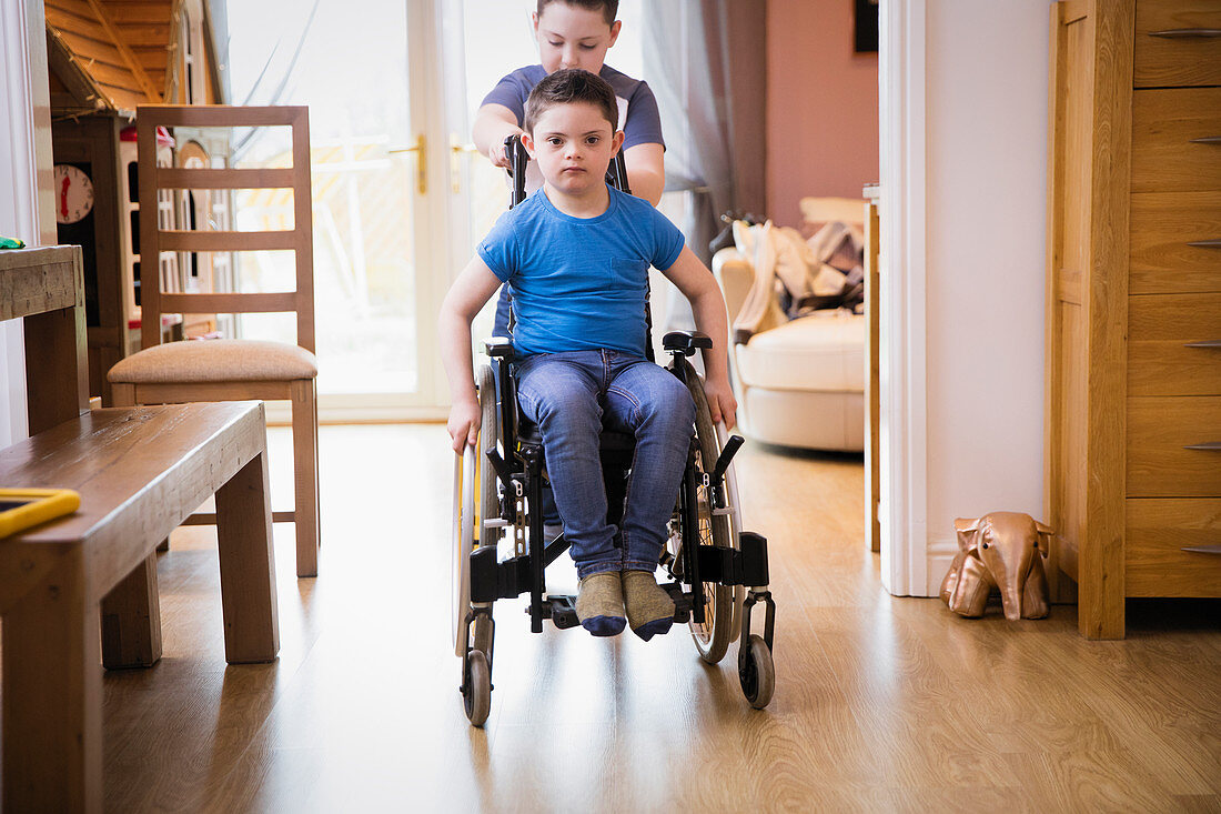 Boy pushing brother with Down Syndrome in wheelchair