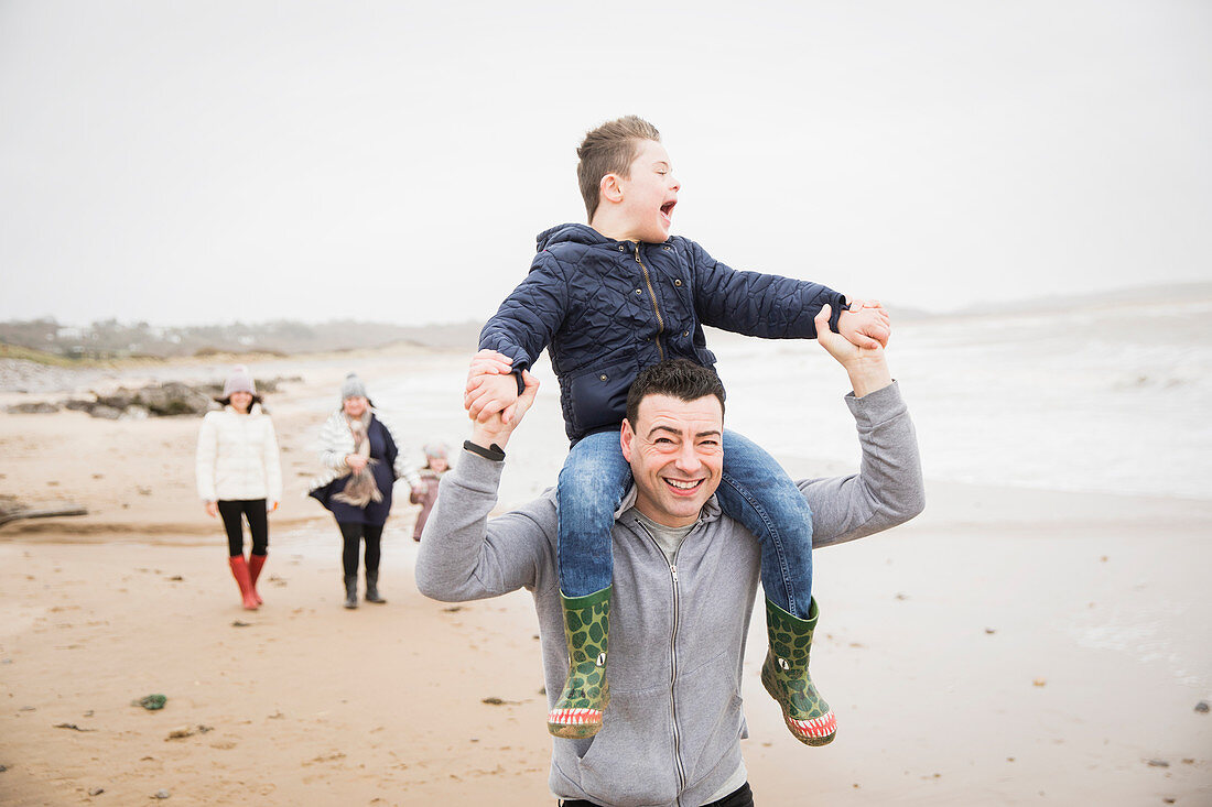 Happy father carrying son with Down Syndrome on shoulders