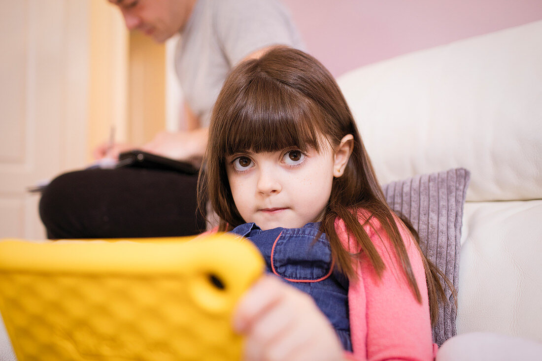 Portrait innocent girl using digital tablet on sofa