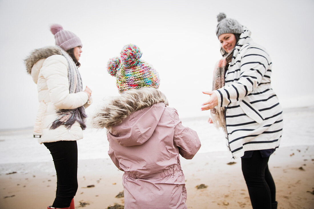 Family in warm clothing on winter ocean beach