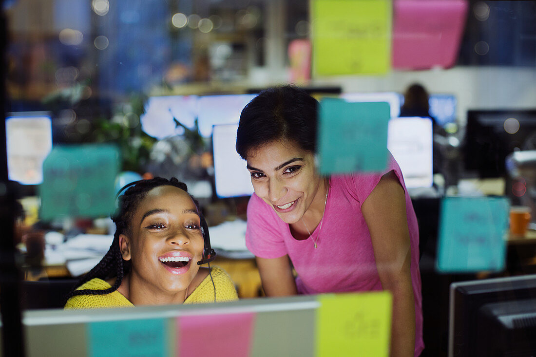Businesswomen using computer behind adhesive notes