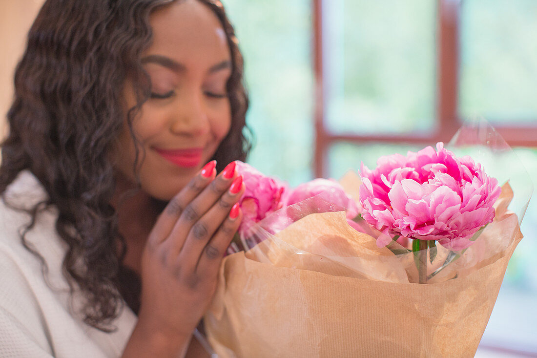 Woman smelling fresh pink peony flower bouquet