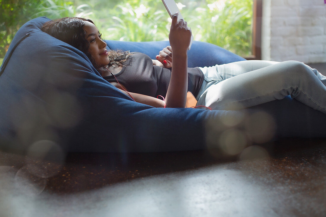 Woman relaxing using digital tablet in beanbag chair