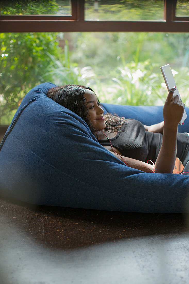 Woman relaxing with digital tablet in beanbag chair