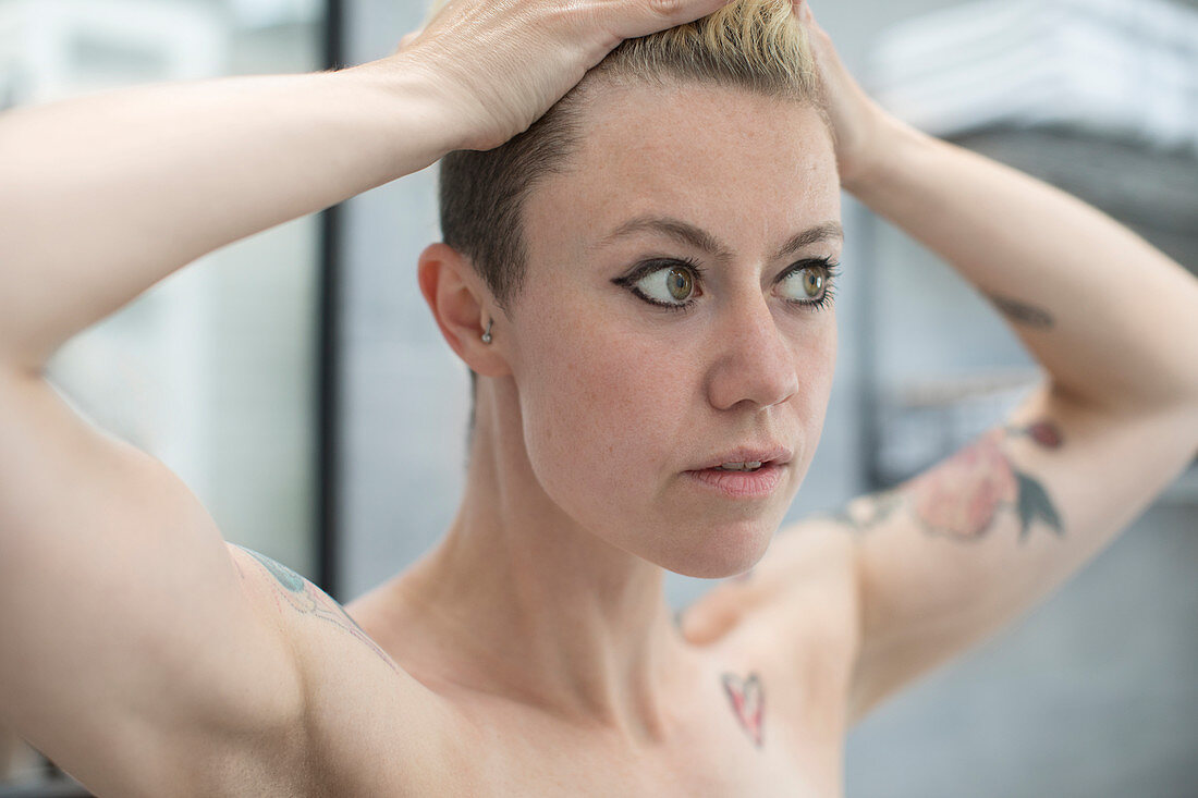 Close up woman with tattoos and hands in hair