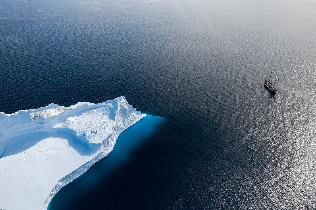 Ship sailing past arctic iceberg on