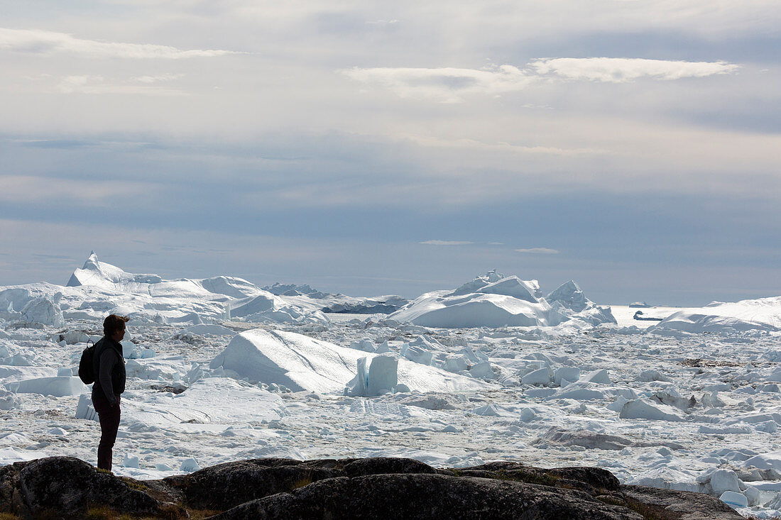 Silhouetted man looking at polar ice melt Greenland