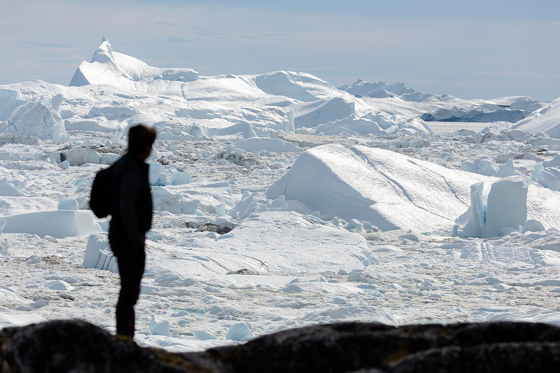 Silhouette man looking at glacial ice melt Greenland