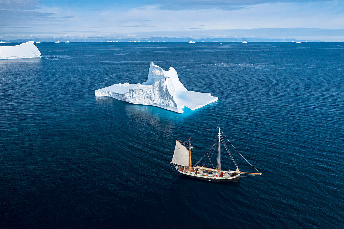 Ship sailing past iceberg on blue Atlantic Ocean Greenland