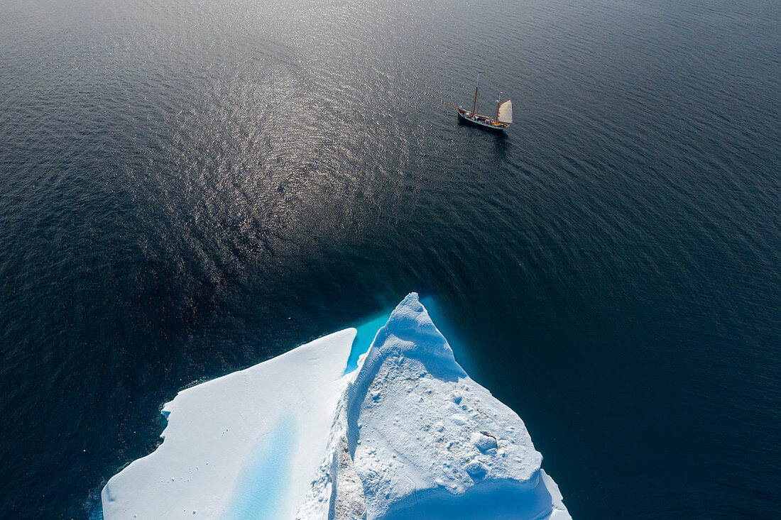 Drone point of view ship sailing past iceberg on ocean