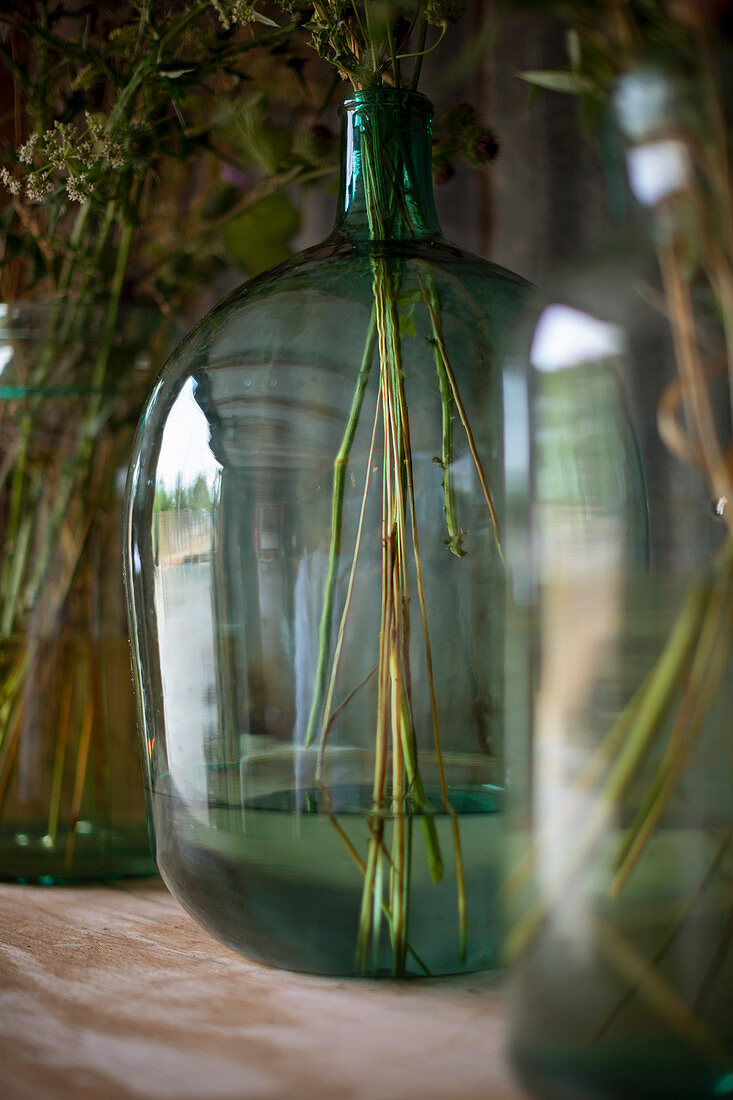 Rustic flowers in clear green glass vase