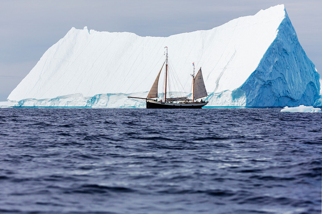 Ship sailing past majestic iceberg on