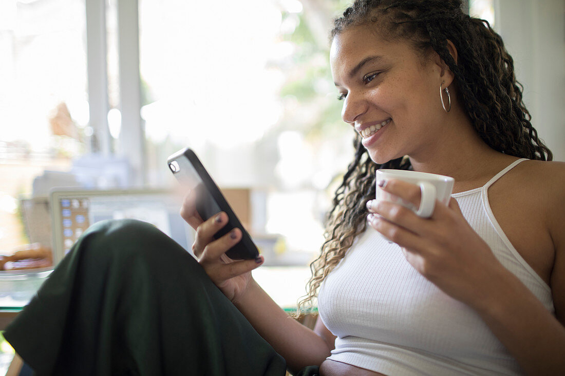 Woman drinking coffee and using smart phone