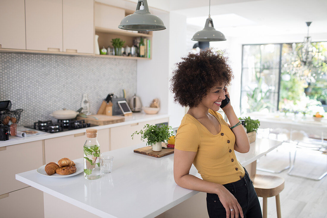 Woman talking on smart phone in kitchen