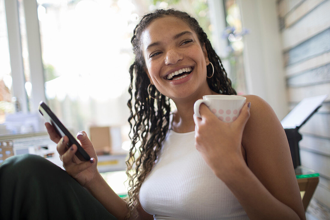 Woman with smart phone and tea laughing