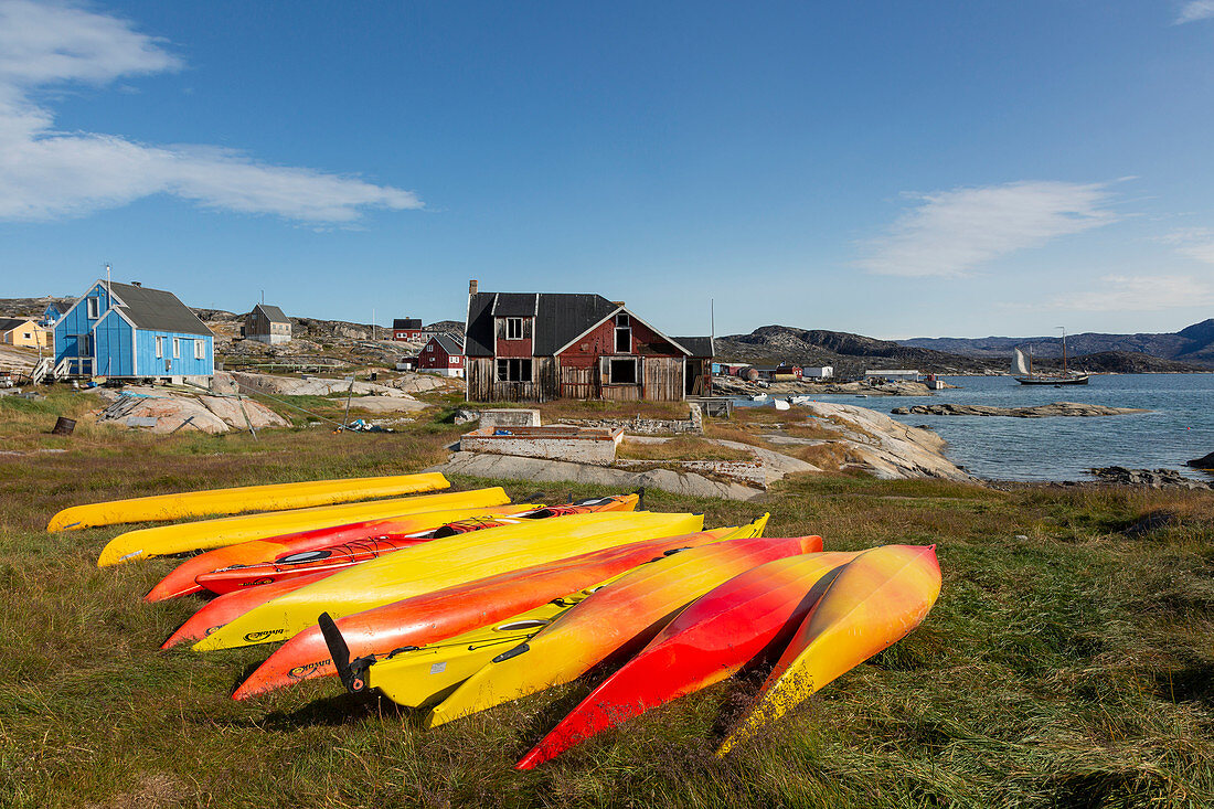 Vibrant coloured kayaks in grass Disko Bay West Greenland